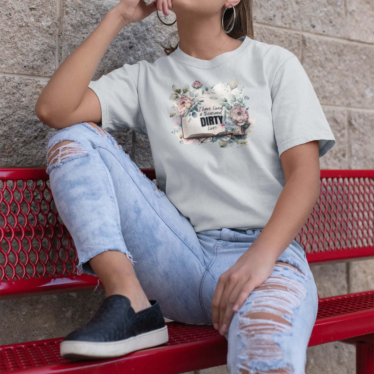 woman on a bench wearing a light grey I have lived a thousand dirty lives tshirt