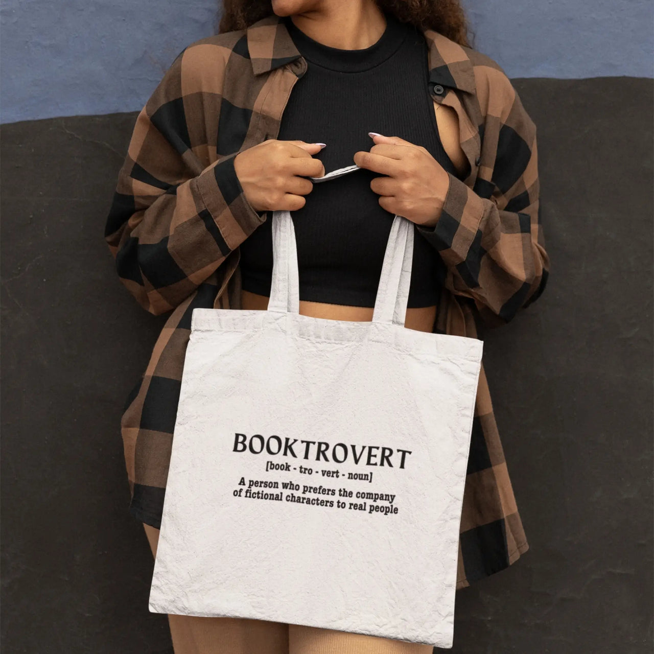 woman carrying a white booktrovert tote in front of her