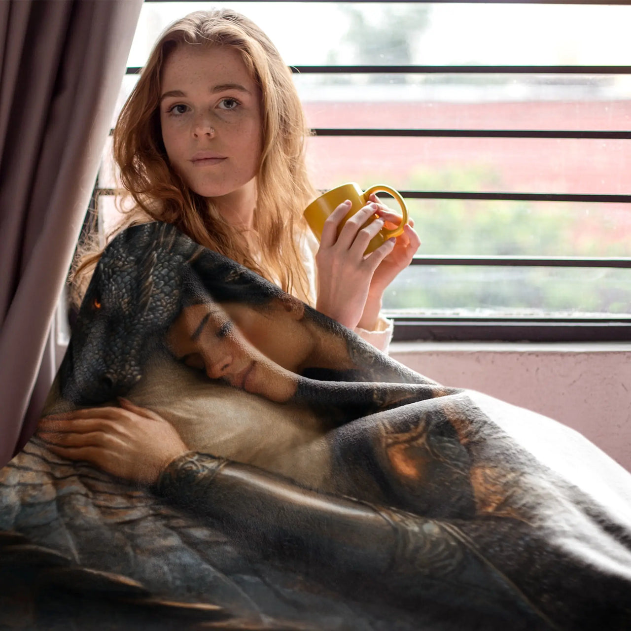 woman drinking a hot beverage while wrapped in the Dragon Bond Blanket