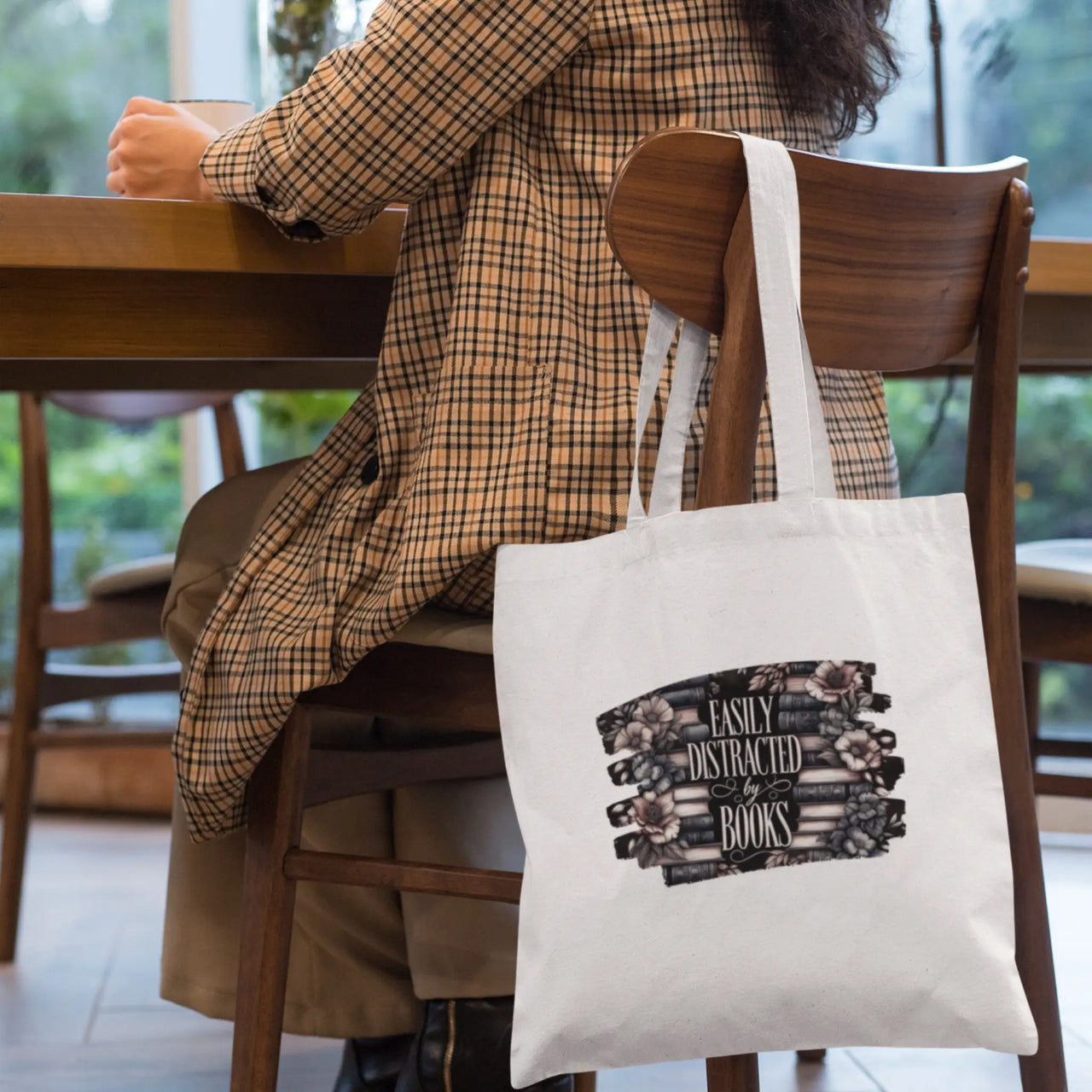 Easily Distracted By books tote bag in white hanging on a chair