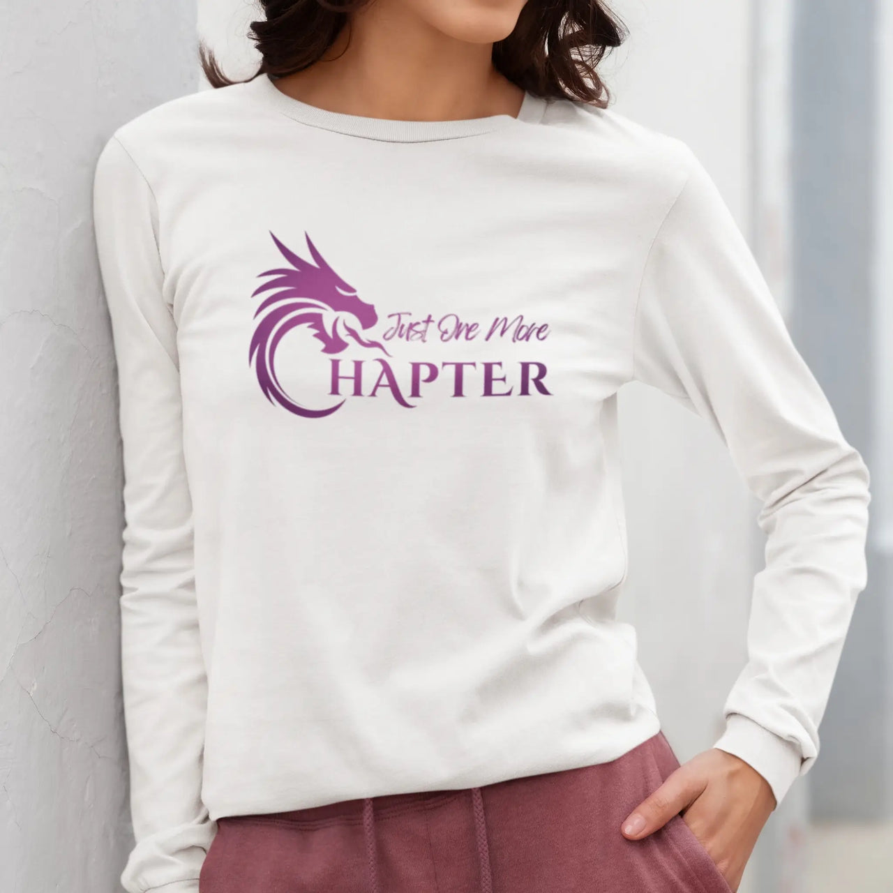 someone wearing a Just One More Chapter Logo design long sleeve in white with purple text