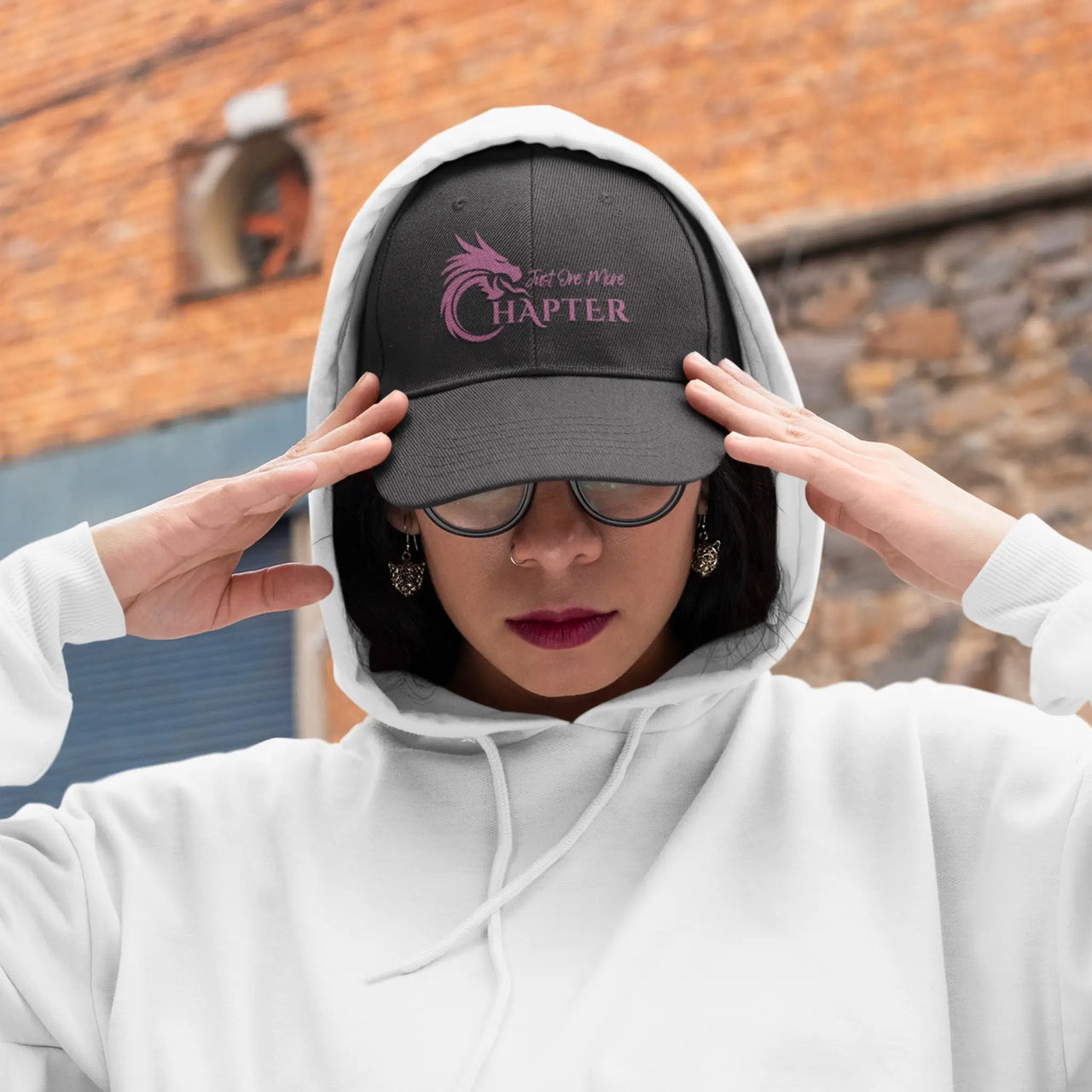 woman wearing a black Just One More Chapter Cap with a hoodie