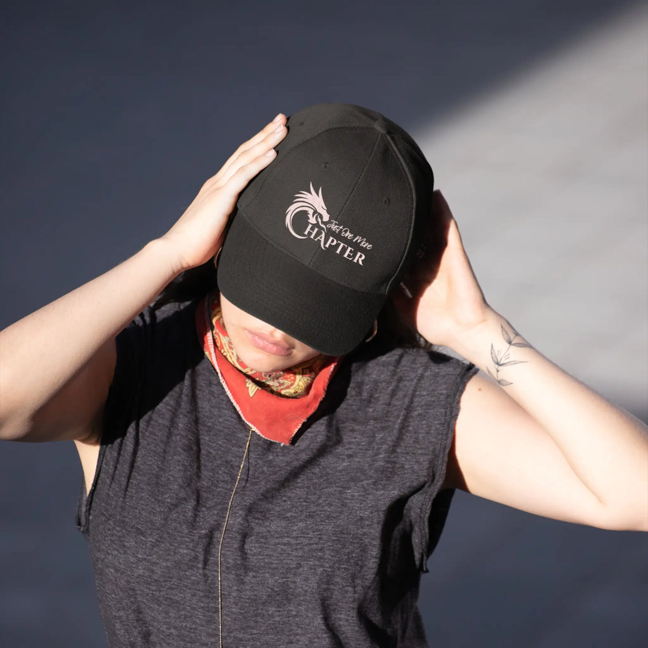 woman wearing a black Just One More Chapter Cap with pink text