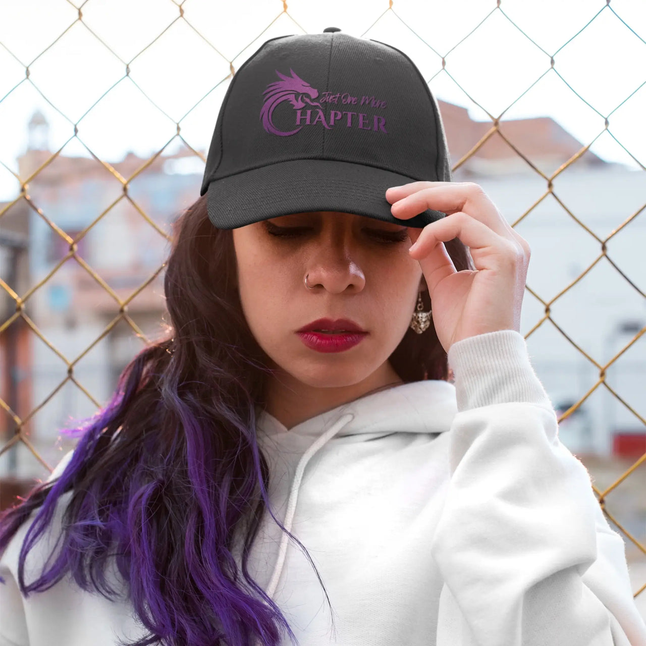 woman wearing a Black Just One More Chapter Cap with purple text