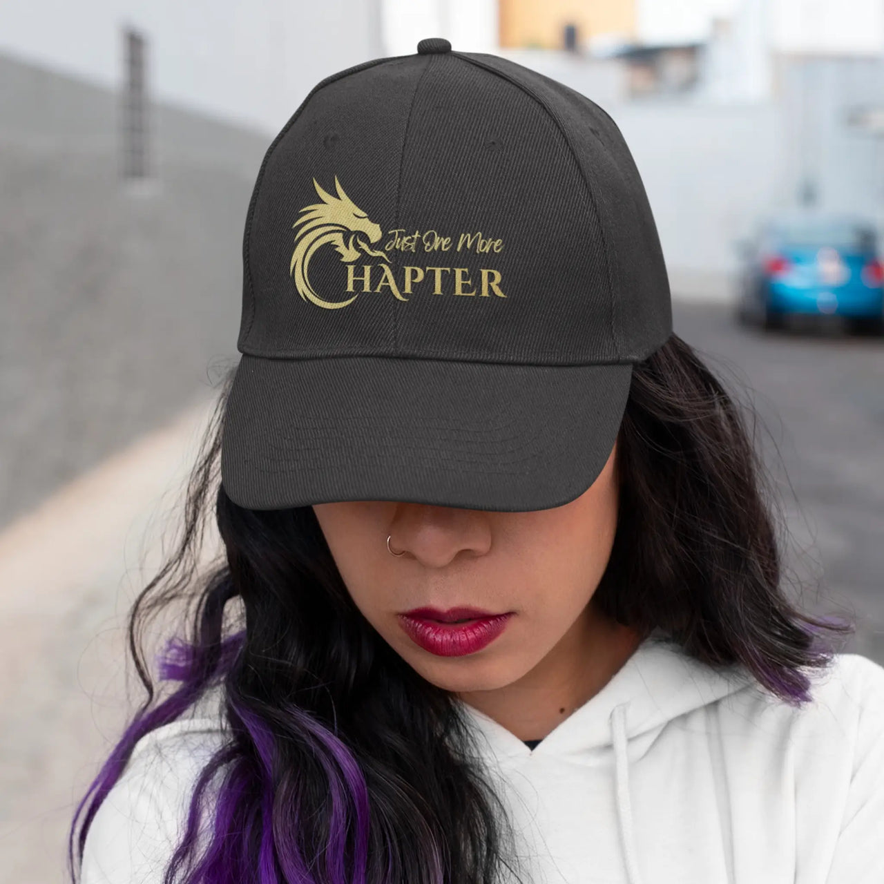 woman wearing a black Just One More Chapter Cap with gold writing