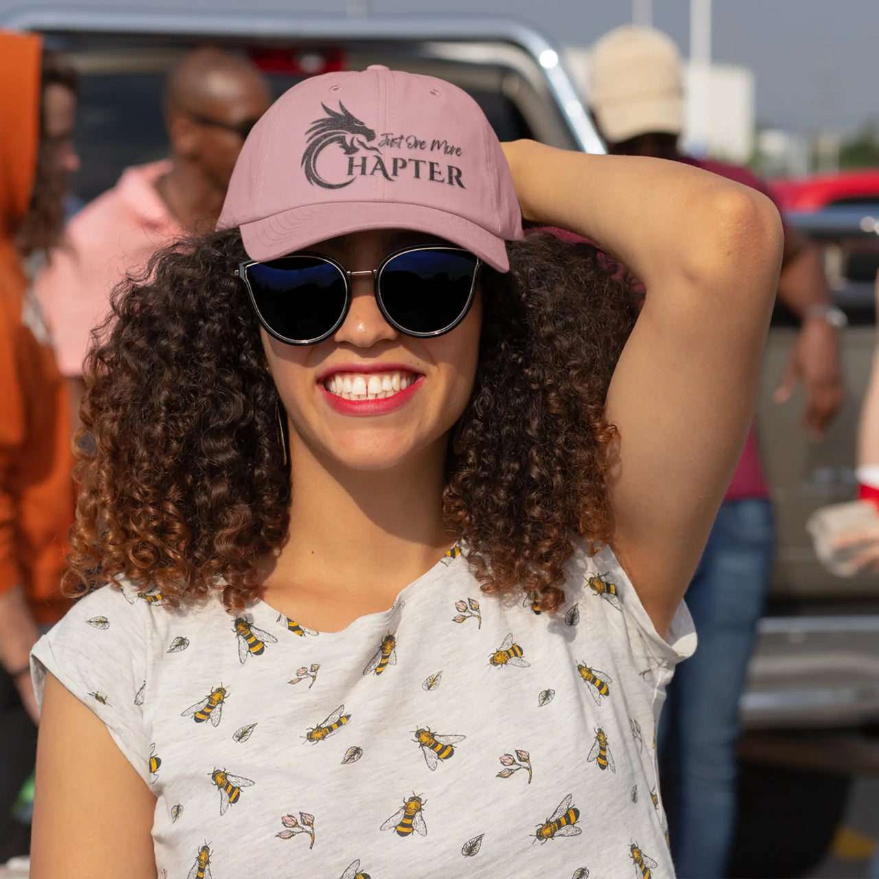 smiling woman wearing a pink Just One More Chapter Cap