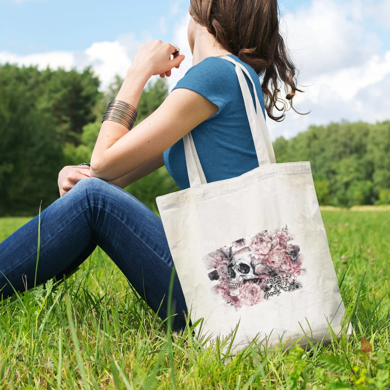 woman sitting in a field with her white morally grey tote