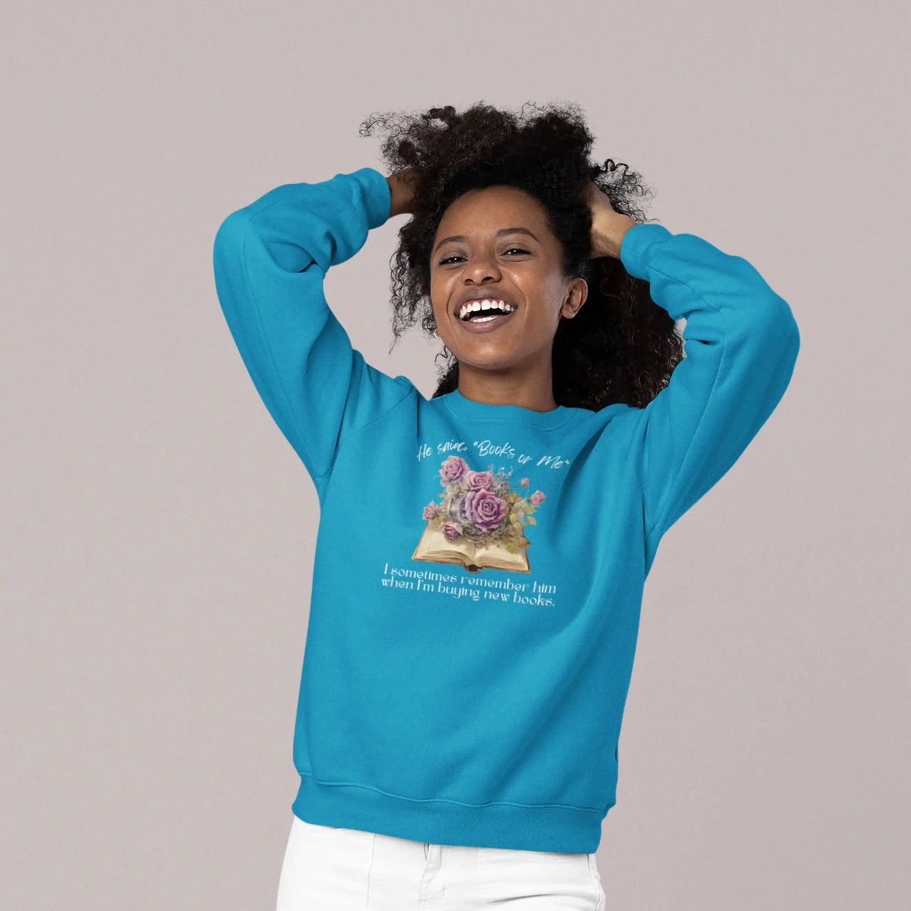 woman showing off her teal Books or Me sweatshirt with white text