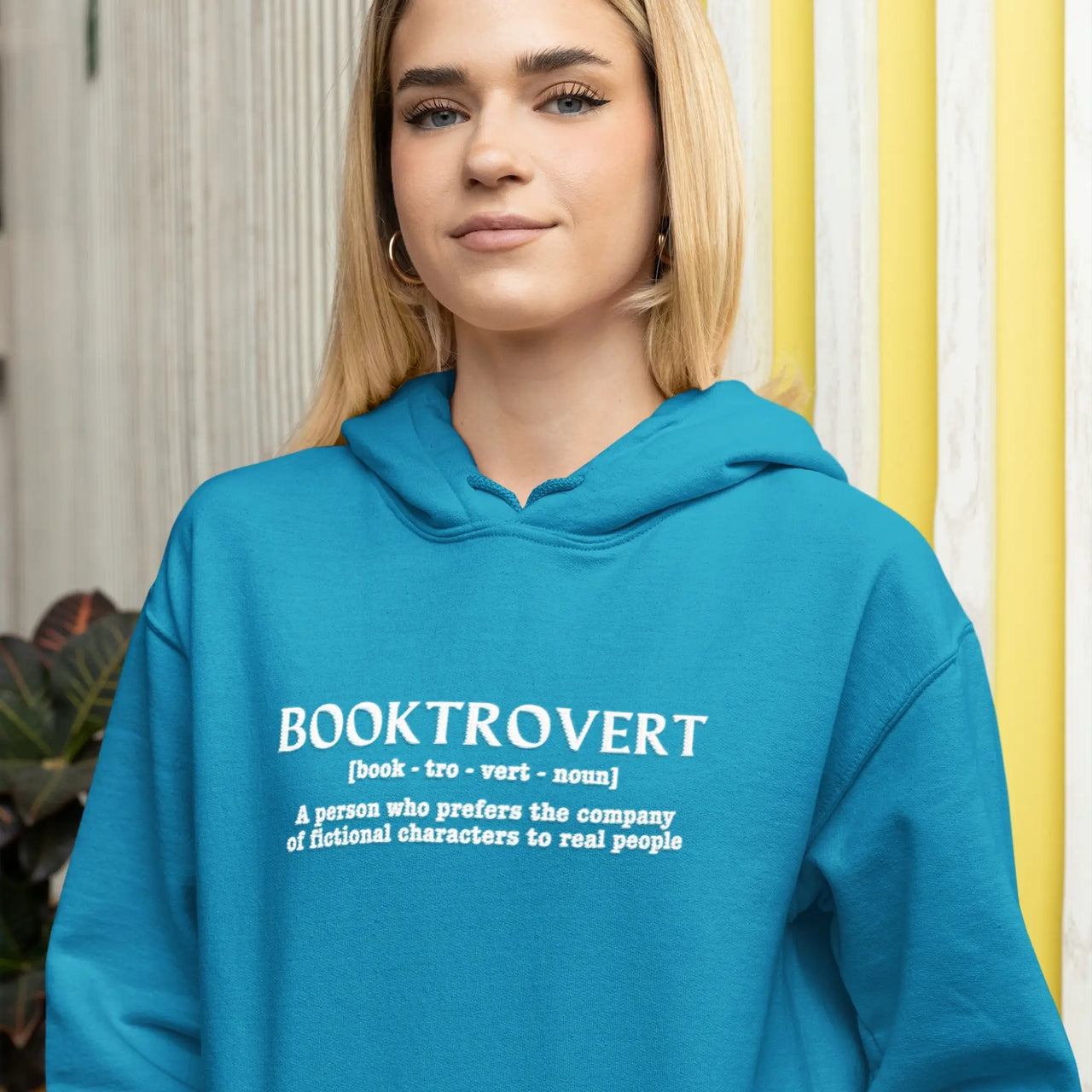 woman wearing the teal booktrovert hoodie with white text