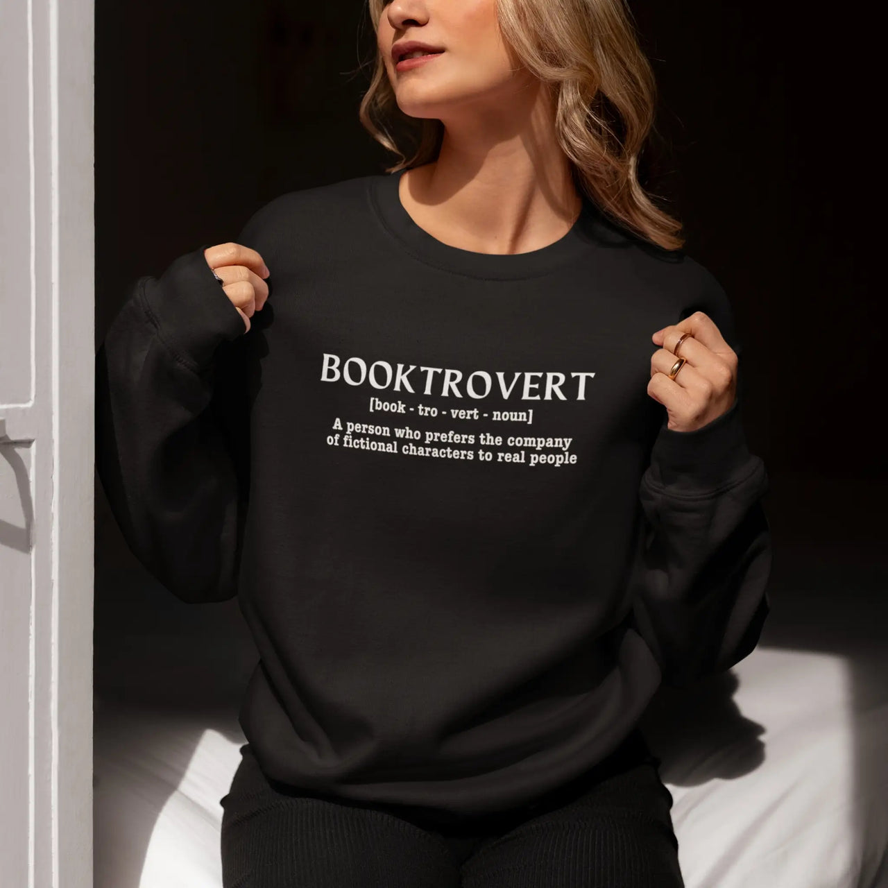 woman wearing a black Booktrovert Sweatshirt with white text