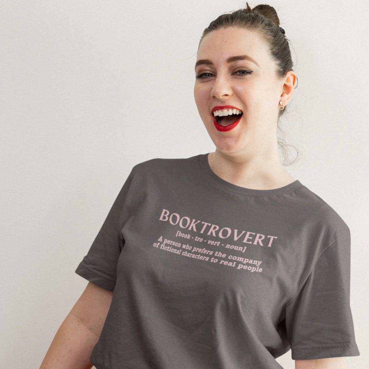 woman wearing a dark grey booktrovert tshirt with pink text