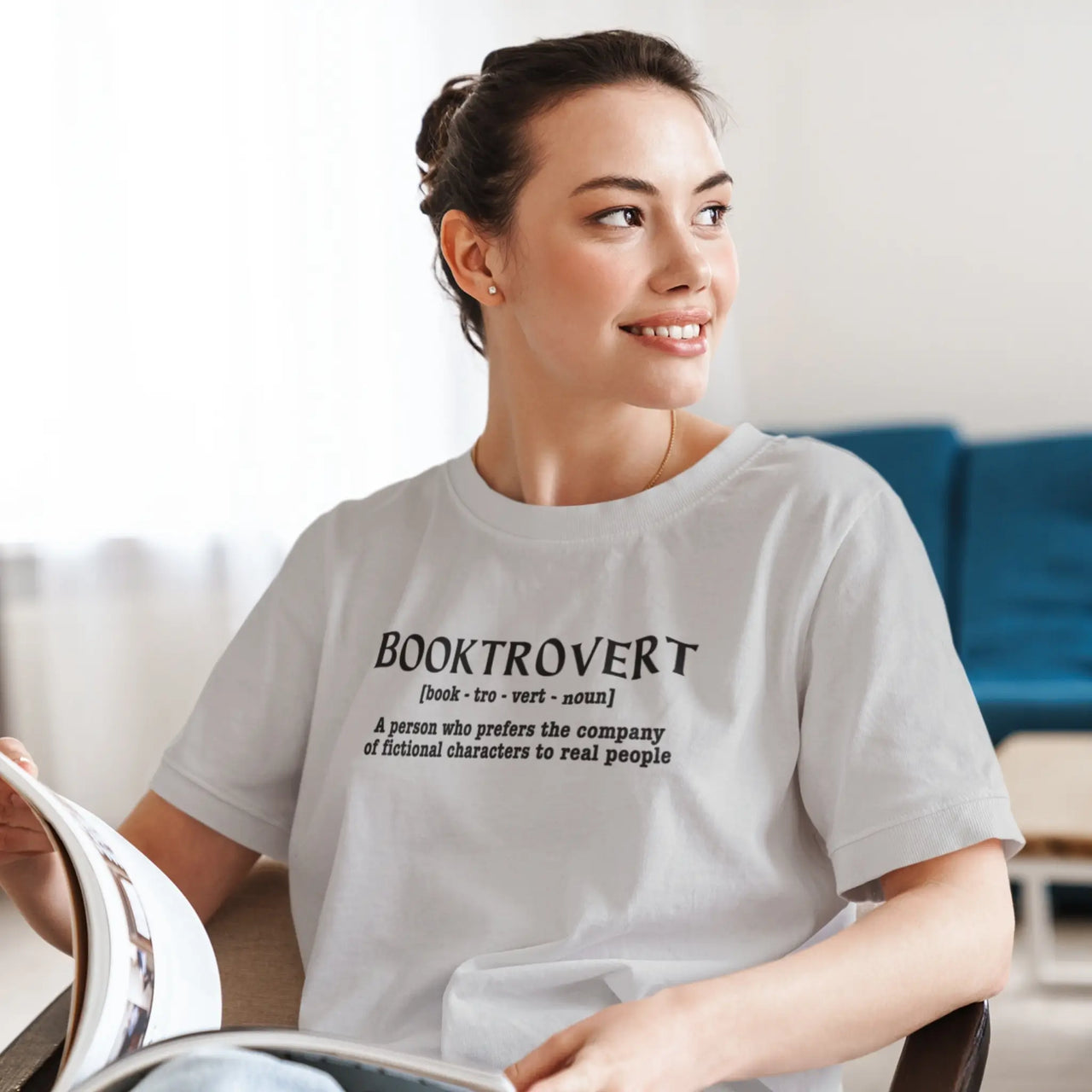 woman reading with a light grey booktrovert tshirt on