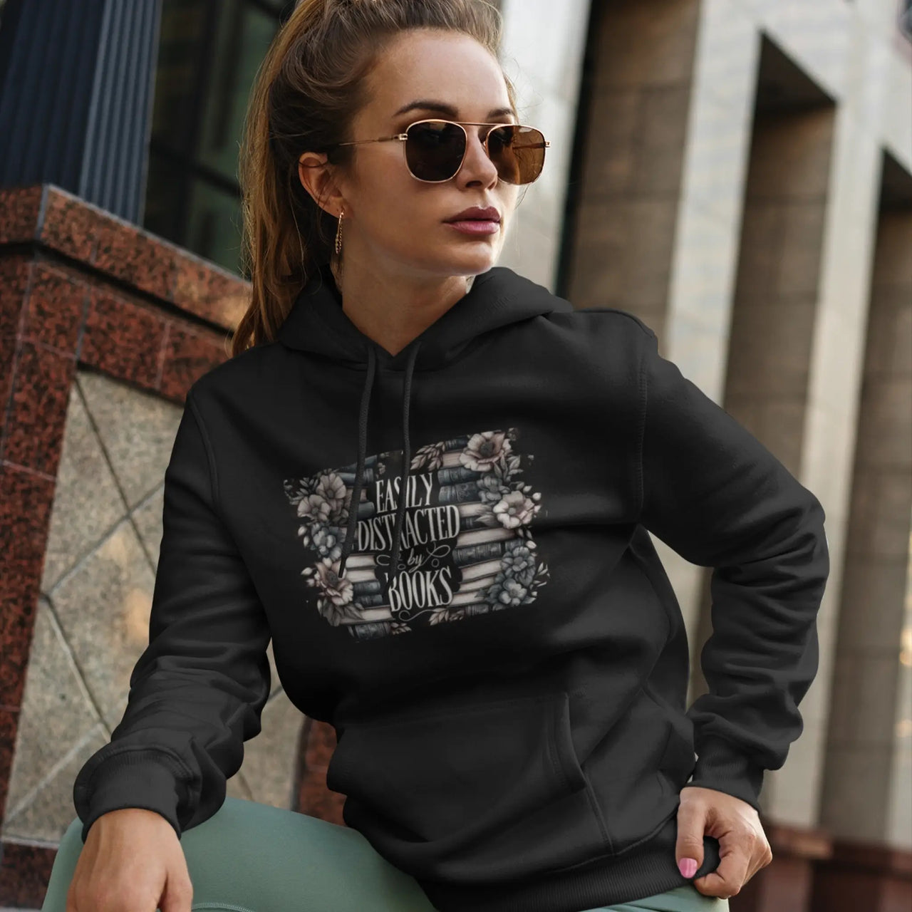 a woman lounging in a a black Easily Distracted By Books Hoodie