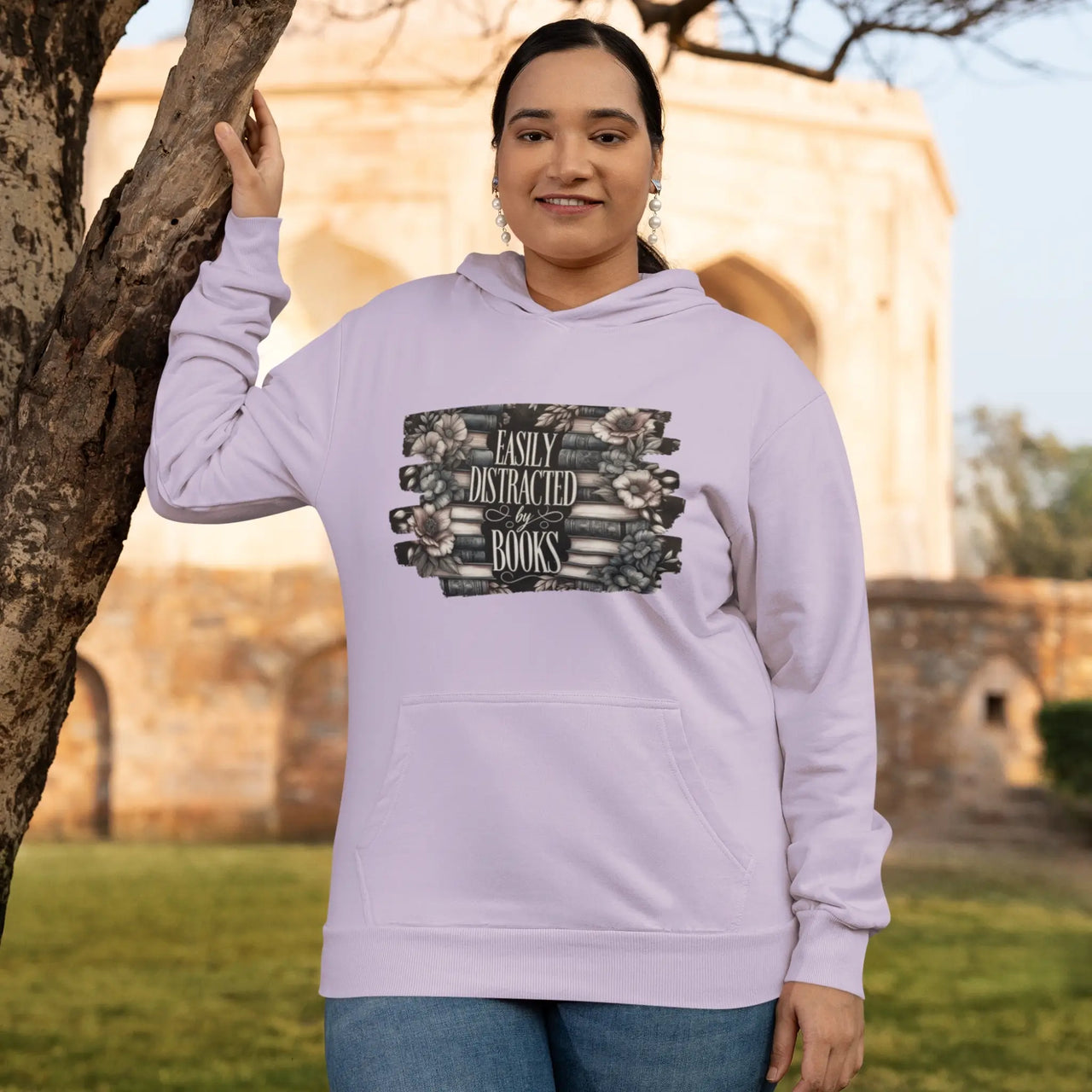 A woman showing off her Orchid Easily Distracted By Books Hoodie