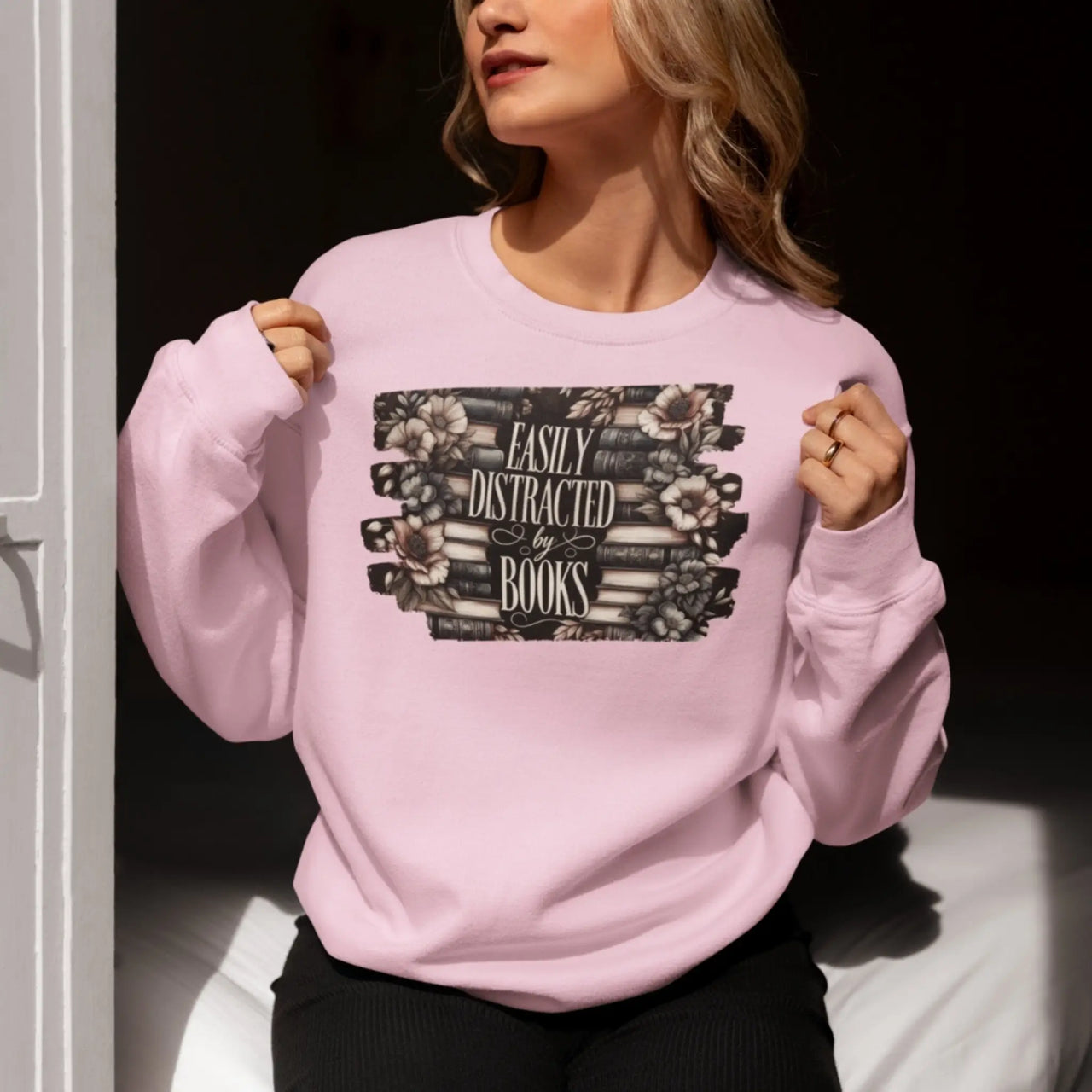 woman posing in a pink Easily Distracted By Books Sweatshirt