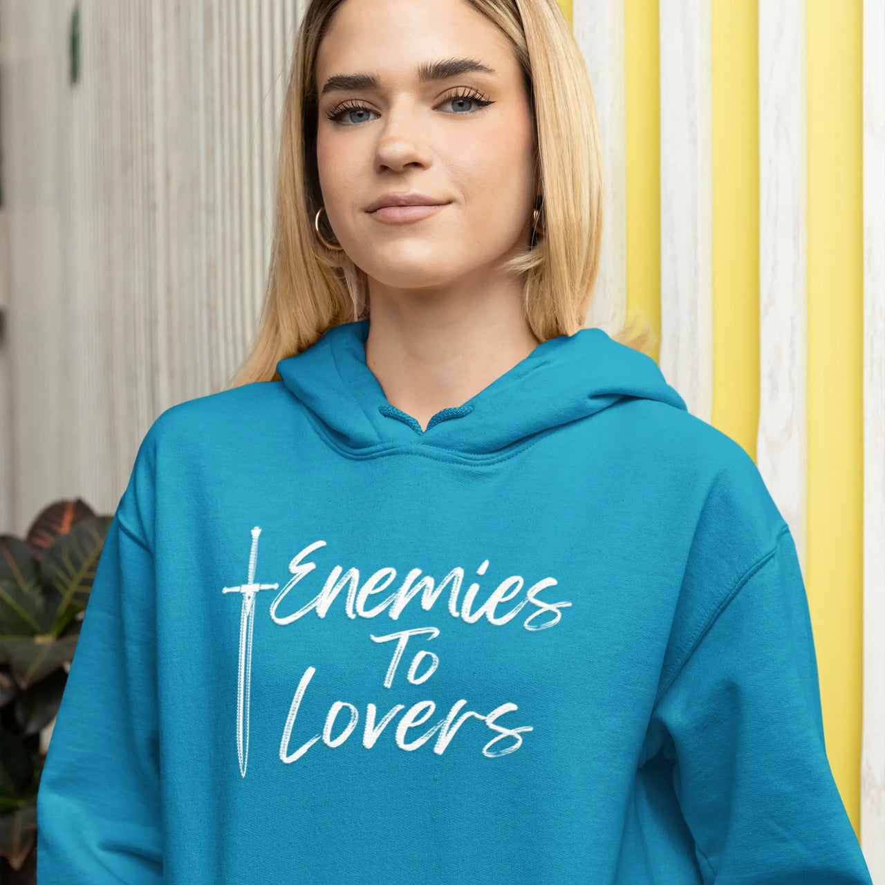 young woman wearing a teal Enemies To Lovers Hoodie with white text