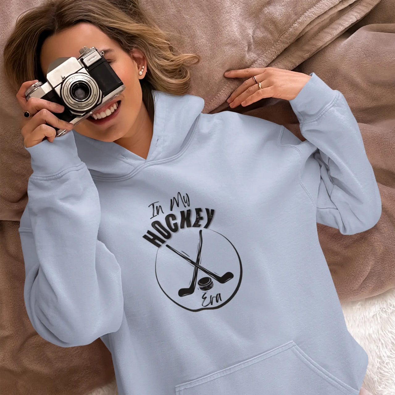 young woman with a camera wearing a Light blue In My Hockey Era Hoodie