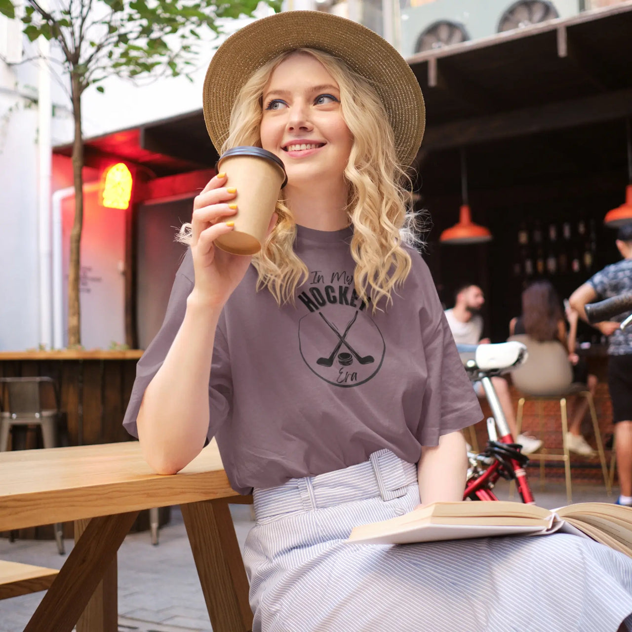 woman reading and drinking coffee while wearing a maroon in my hockey era tshirt