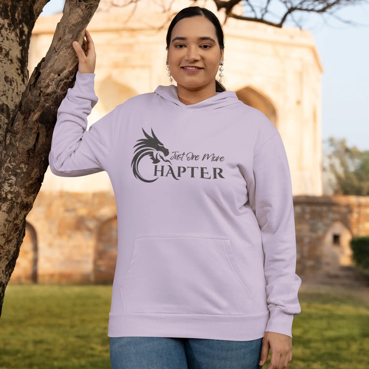 woman wearing a an orchid Just One More Chapter Hoodie V1 with black text