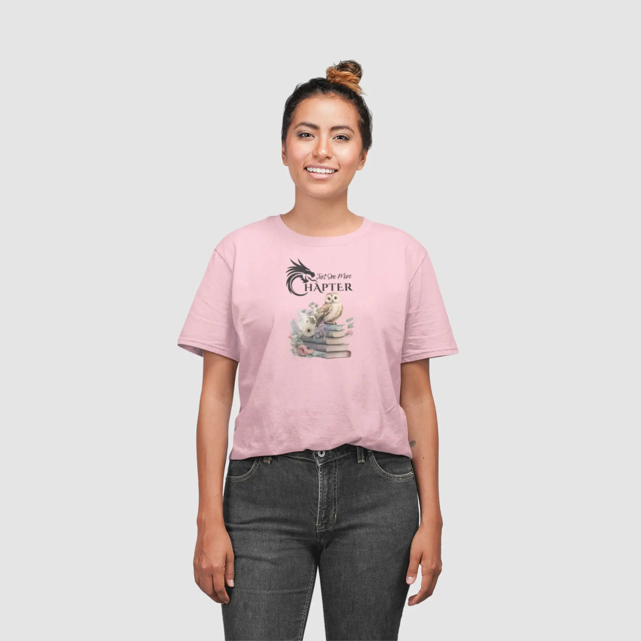 woman posing wearing a Light pink Just One More Chapter T-shirt V3 with black text