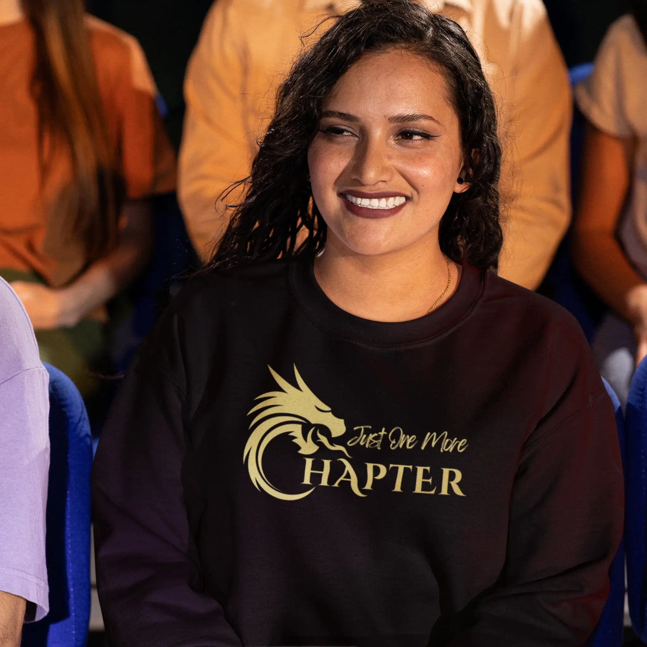 woman wearing a black Just One More Chapter sweatshirt with gold text