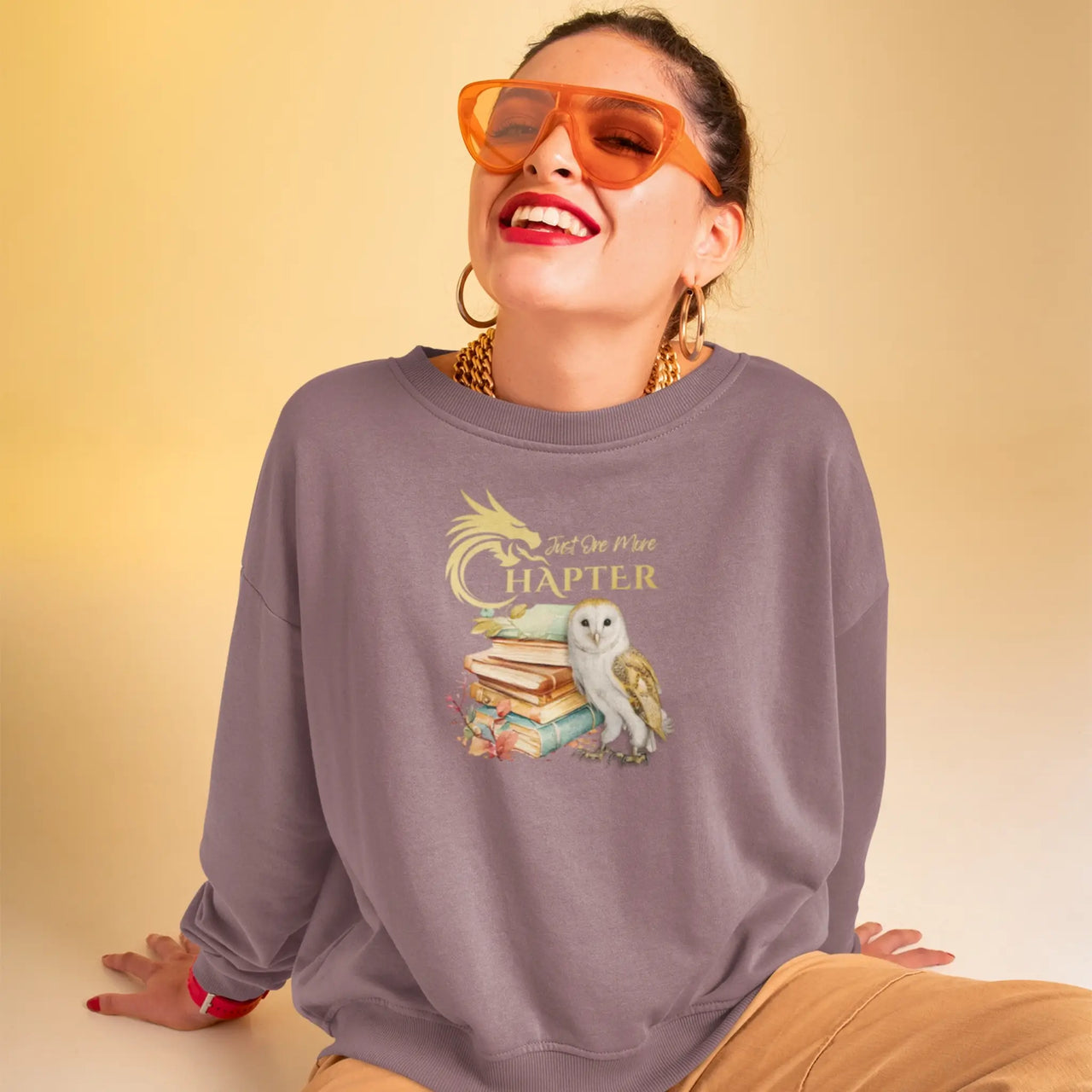 happy woman wearing a Maroon Just one more chapter sweatshirt v2 with gold text