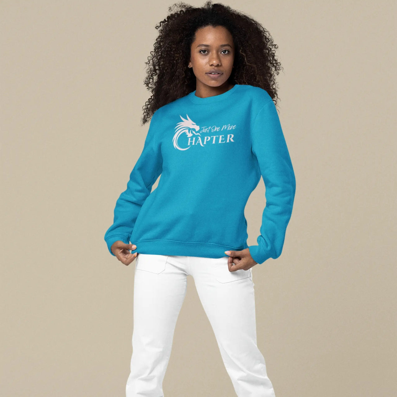 young woman wearing a teal Just One More Chapter sweatshirt with pink text