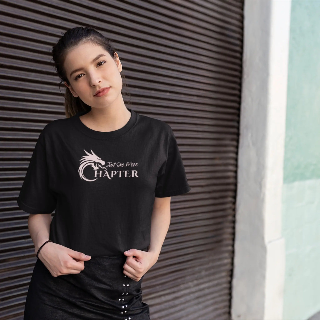 woman wearing a black Just one more chapter tshirt with pink text