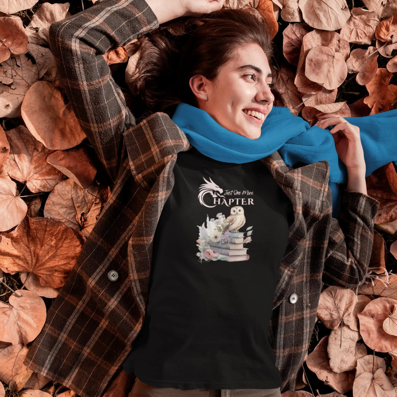 woman lying in leaves wearing a black  Just One More Chapter T-shirt V3 with pink text