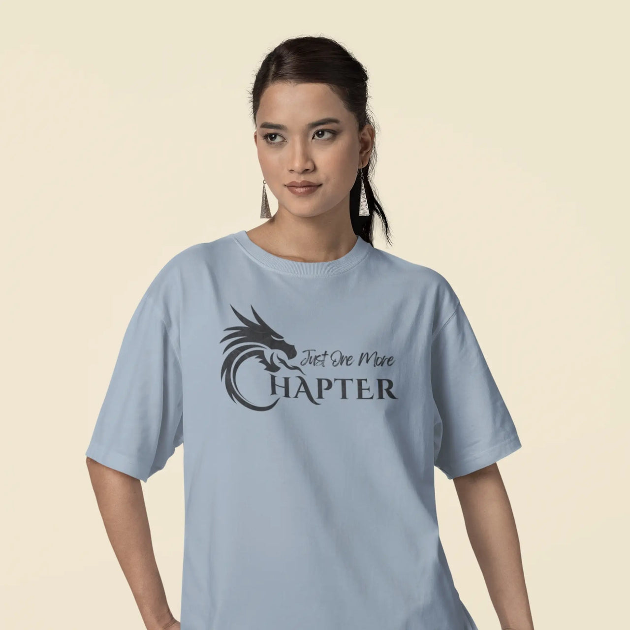 woman wearing an oversized light blue Just one more chapter tshirt with black text