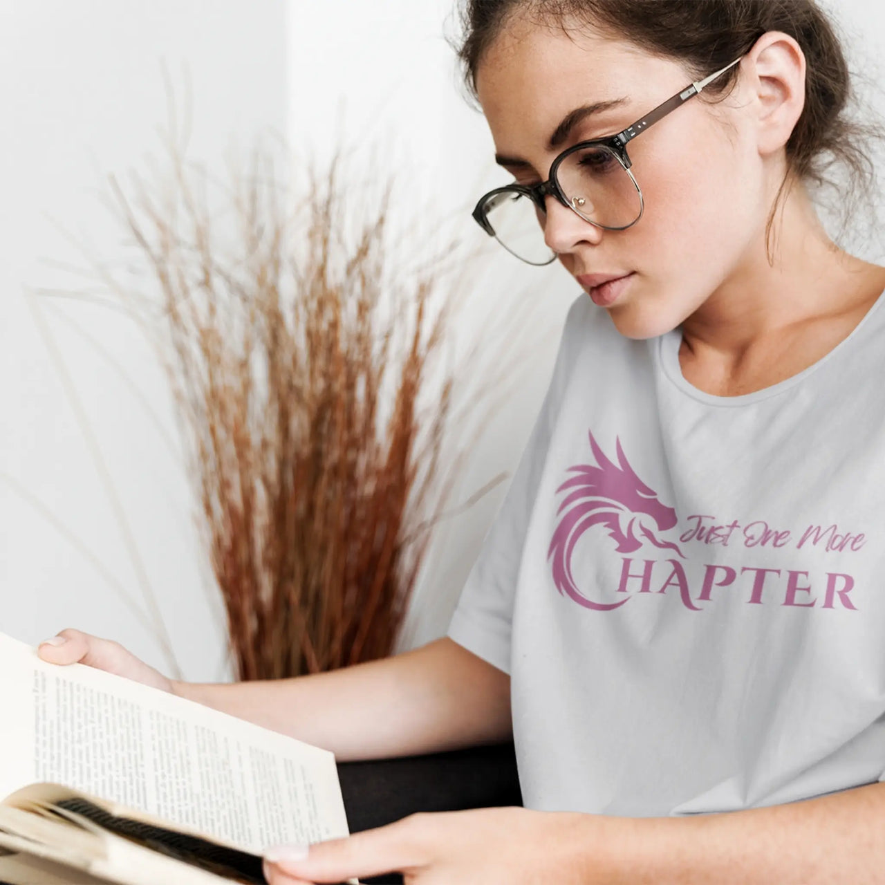 young woman reading wearing a light grey Just one more chapter tshirt with purple text