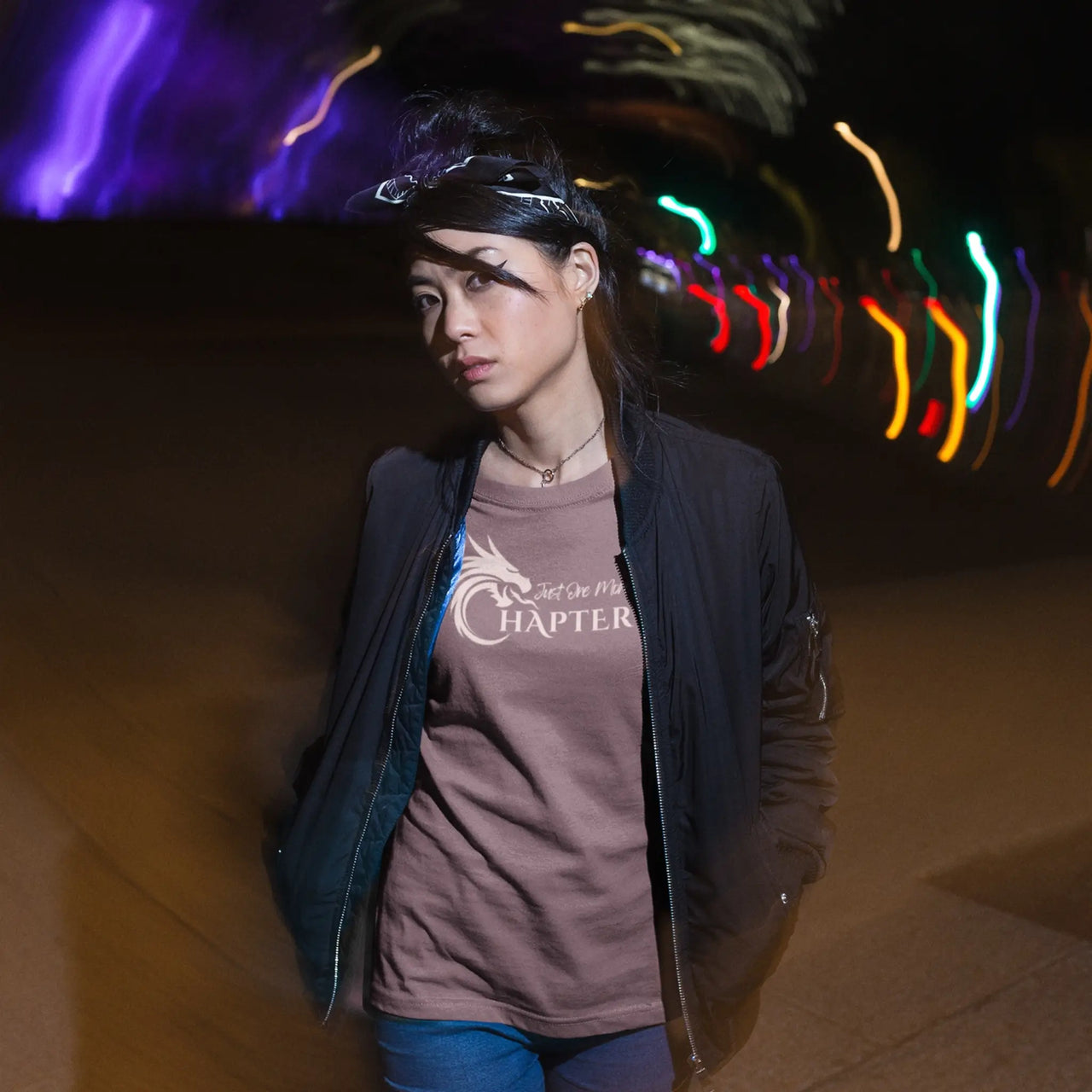 woman showing off the maroon Just one more chapter tshirt with pink text