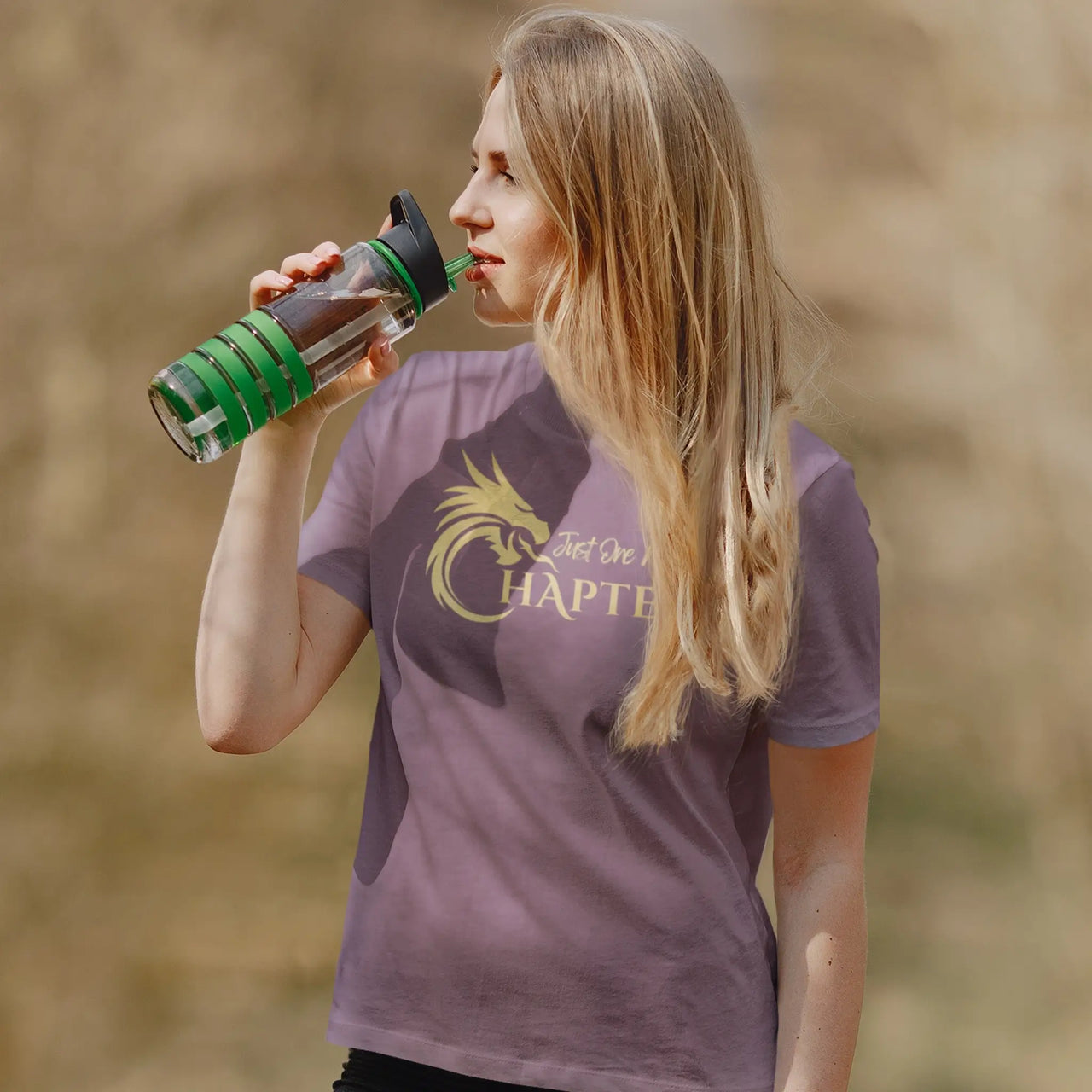 maroon Just one more chapter tshirt with gold text being worn by a woman drinking water