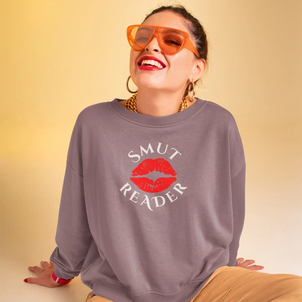 woman with sunglasses wearing our maroon smut reader sweatshirt with white text