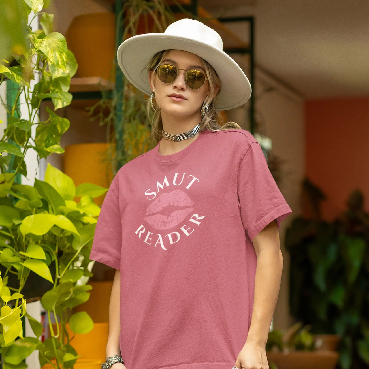 woman in a hat with sunglasses wearing a dark pink smut reader t-shirt pink lips